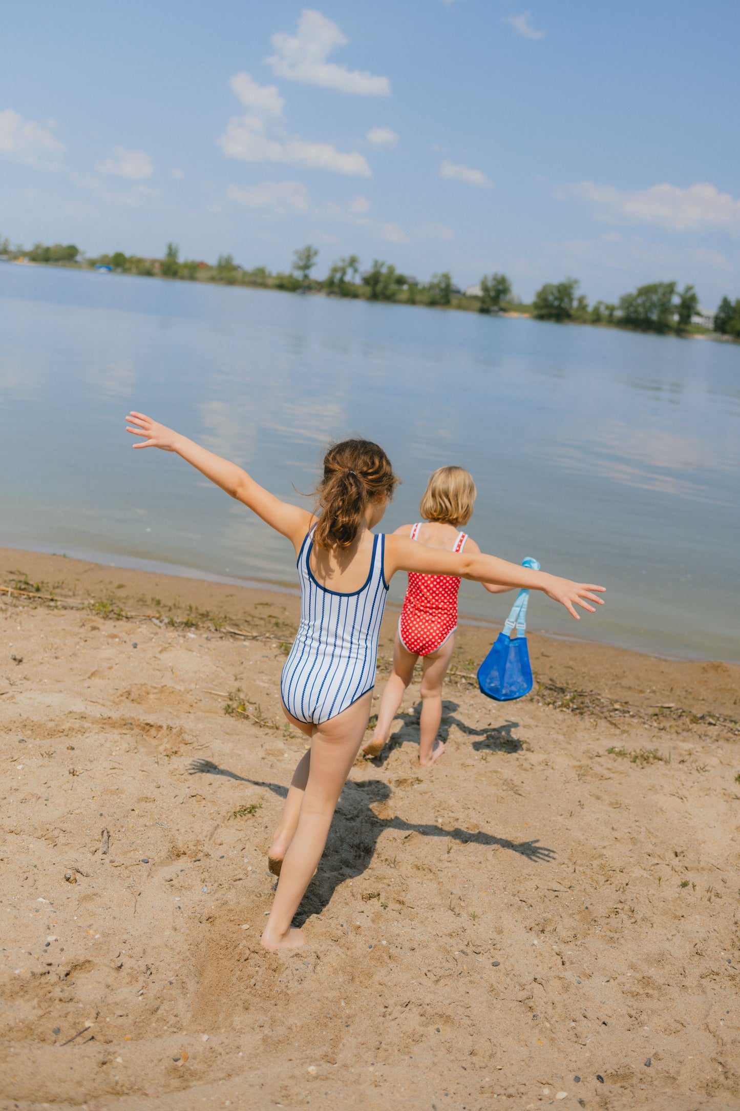 Two children playing on a sandy beach by a lake